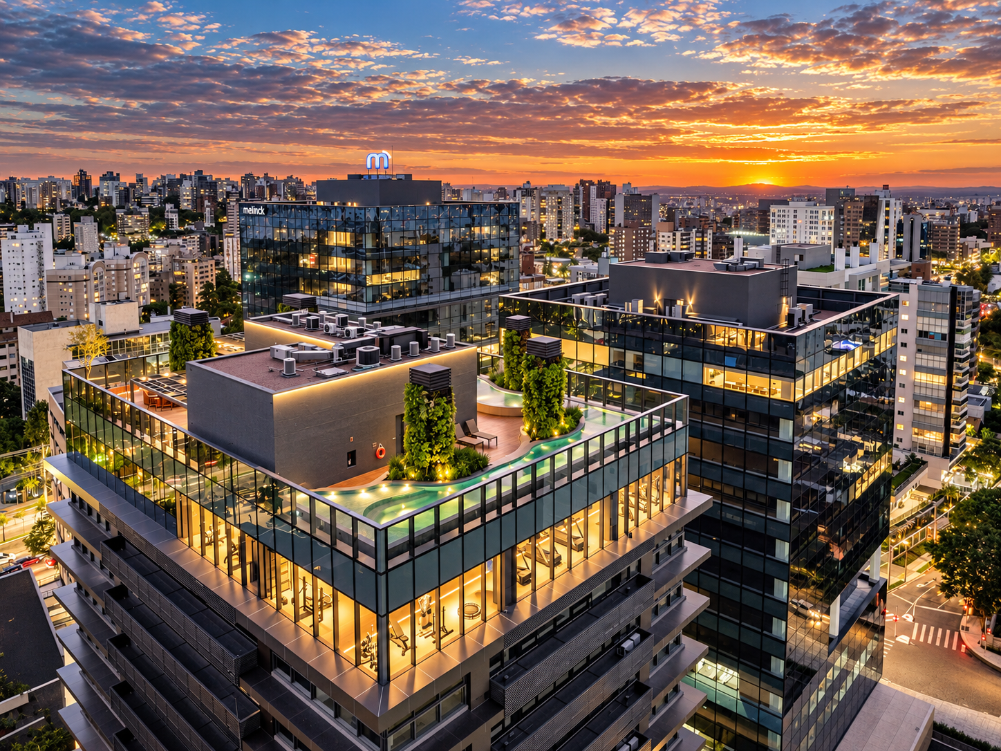 Vista aérea do complexo ao entardecer, com o terraço com piscina no topo